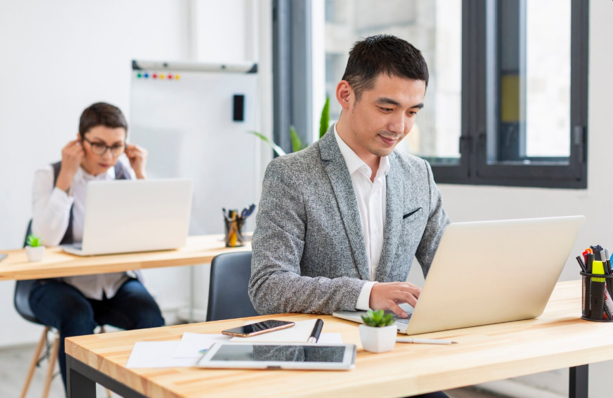 employee using employer education benefits programs while working on laptop in office